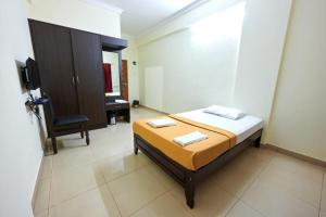 um quarto com uma cama e uma cadeira em Hotel Down Town em Manipala