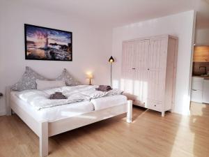 a white bedroom with a large white bed in a room at Ruhiges 1-Zimmer-Appartement, Büsum (4km), Nordsee in Oesterdeichstrich