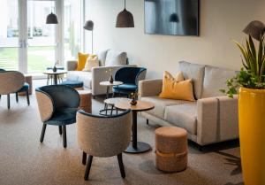uma sala de estar com um sofá, cadeiras e mesas em JUFA Hotel Bad Radkersburg - inkl 4h Thermeneintritt em Bad Radkersburg