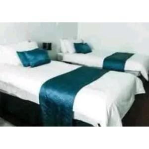 two beds in a hotel room with blue pillows at Brakendene Lodge in Gaborone