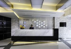 a man standing behind a reception desk in a lobby at Popway Hotel in Hong Kong