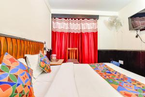 a bedroom with a bed and a red curtain at FabHotel Park View I in Manāli