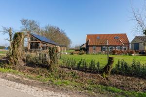 a farm with a house and a field of crops at Welcome in - Rustig gelegen gastenverblijf met eigen tuin, slaapkamer en badkamer in Koudekerke