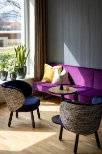 um sofá roxo numa sala de estar com uma mesa e cadeiras em JUFA Hotel Bad Radkersburg - inkl 4h Thermeneintritt em Bad Radkersburg