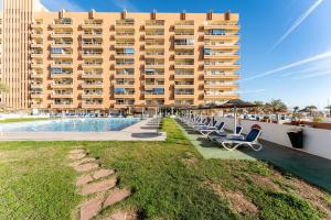 フエンヒロラにあるMarina view, sunny one bedroom pyrのプールとラウンジチェア付きの大きな建物