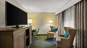 ブルーミントンにあるハンプトン イン ブルーミントンの薄型テレビ、椅子が備わるホテルルームです。