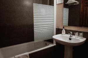 een badkamer met een wastafel, een spiegel en een bad bij Hostal Café FRENTEABASTOS in Carmona