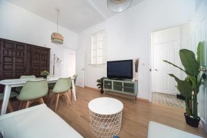 ein Wohnzimmer mit einem TV, einem Tisch und Stühlen in der Unterkunft Apartment Mosaic Giralda in Sevilla