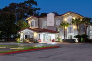 a large white building with palm trees in front of it at La Quinta Inn by Wyndham Pensacola in Pensacola