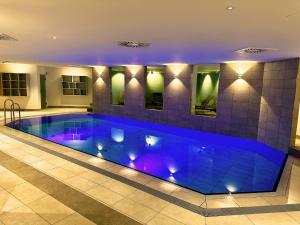 a swimming pool in a house with purple lighting at Augustiner Hotel in Hillesheim