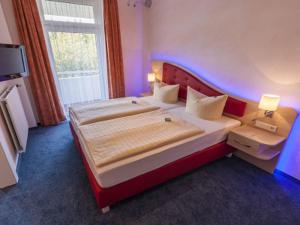 a bedroom with a large bed with a red headboard at Hotel Hochsauerland 2010 in Willingen