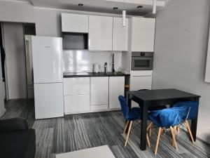 ブィドゴシュチュにあるApartament z kuchnią dla 4 osób w centrum Bydgoszczyのキッチン(白いキャビネット、黒いテーブルと椅子付)