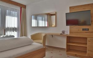 Habitación de hotel con cama y TV de pantalla plana. en Hotel Moawirt, en Wagrain