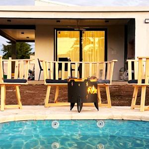 - un foyer extérieur assis à côté de deux chaises à côté de la piscine dans l'établissement Te veo bien, à Suipacha