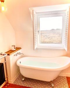 een badkamer met een wit bad en een raam bij Kinnoull House near Stornoway Hot Tub/Pet Friendly in Garrabost