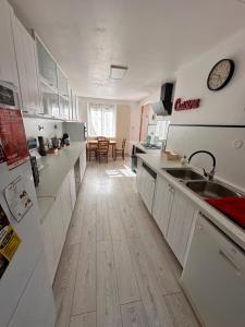 una cucina con armadietti bianchi e pavimenti in legno di La Souste appartement avec jardin privatif a La Fare-en-Champsaur