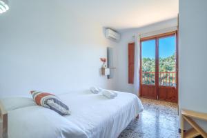 a white bedroom with a bed and a balcony at G398 Ses Savines by Mallorca Villa Selection in Santanyi