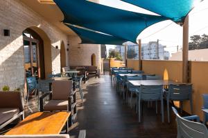 a restaurant with tables and chairs and a blue umbrella at Mahdia - Baghdadi - Laourient Apartments, restaurant, café in Mahdia