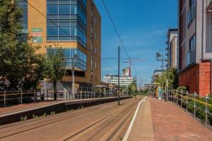 an empty street in a city with tall buildings at Entire 2BR Flat Rental in Manchester City Centre in Manchester