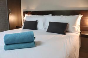 a white bed with a blue pillow on it at The Ultimate Lodge in Louis Trichardt