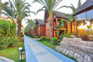 uma casa com palmeiras ao lado de uma rua em Long Beach Alanya - Ultra All Inclusive em Avsallar