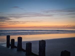 a sunset on a beach with posts in the sand at The Penthouse NY Loft Apartment in Barmouth