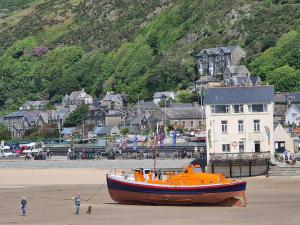 a boat sitting on the sand on a beach at The Penthouse NY Loft Apartment in Barmouth