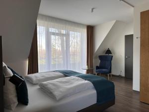 a bedroom with a large bed and a blue chair at Hotel Schöne Aussicht in Wilhelmshaven