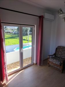 um quarto com uma porta de vidro deslizante e uma cadeira em Casa O Limoeiro em Ponte de Lima