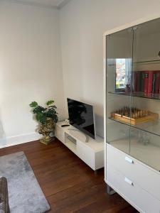 ein Wohnzimmer mit einem TV und einem Glasschrank in der Unterkunft Casa Pinos City in Friedrichshafen