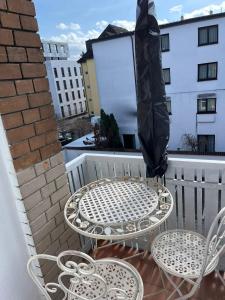 ein Tisch und zwei Stühle und ein Sonnenschirm auf dem Balkon in der Unterkunft Casa Pinos City in Friedrichshafen