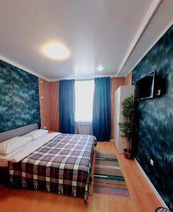 a bedroom with a bed with blue curtains and a tv at ZhanHotels in Almaty