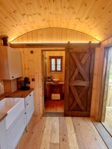 a kitchen with a wooden door with a sink at Shepherds Hut/Hot Tub Private Lake Jurassic Coast in Bridport