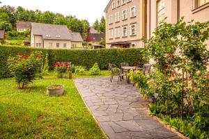 a patio with a table and chairs in a garden at Ferienwohnung - Blumenstraße in Sebnitz