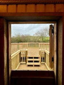 an open door to a deck with a bench on it at Shepherds Hut/Hot Tub Private Lake Jurassic Coast in Bridport