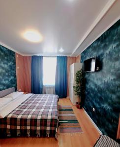 a bedroom with a bed and a tv on a wall at ZhanHotels in Almaty