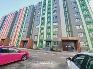 a pink car parked in front of a tall building at ZhanHotels in Almaty