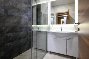 Inđija的住宿－Monogramlux，一间带水槽和玻璃淋浴的浴室