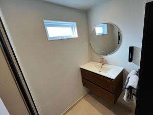 ein Bad mit einem Waschbecken und einem Spiegel in der Unterkunft Huisje bij Zee (gratis parkeren) in Noordwijk aan Zee