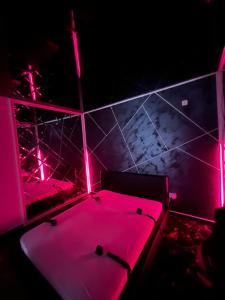 um quarto com luzes cor-de-rosa num quarto com uma banheira em Adult only fantasy room em Bucareste