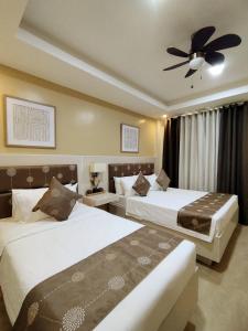 a bedroom with two beds and a ceiling fan at Casa Marta Hotel in Iloilo City