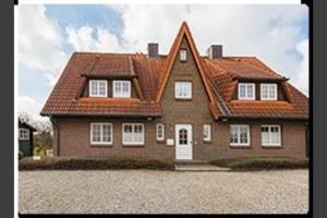 a large brown house with a red roof at Syltnest in Munkmarsch