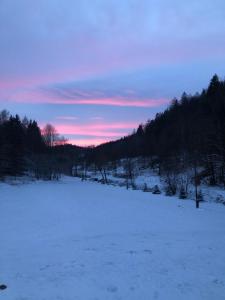 a field covered in snow with a sunset in the background at Apartamenty ARNIKA in Lądek-Zdrój