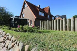 a brick house with a fence in front of it at Sylter Zuhause in Munkmarsch