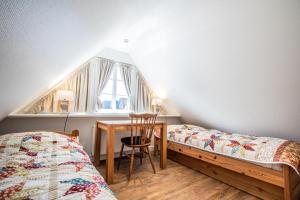 a bedroom with two beds and a table and a window at Haus Twesk Merre in Munkmarsch