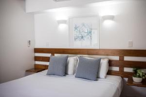 sypialnia z dużym białym łóżkiem z niebieskimi poduszkami w obiekcie Port Douglas Peninsula Boutique Hotel - Adults Only Haven w mieście Port Douglas