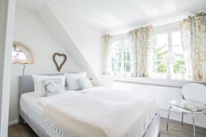 a white bedroom with a bed and a window at Haus Munkhoog in Munkmarsch