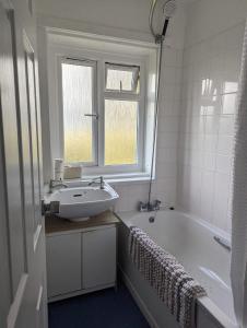 a bathroom with a sink and a tub and a window at Stunning 3Bed Seaview Downs National park House in Rottingdean