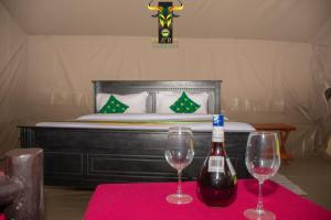 dos copas de vino en una mesa con una cama en Mara Olodare, en Ololaimutiek