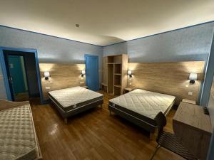 ヴィック・フェザンサックにあるHotel Le D'artagnanの青い壁とウッドフロアの客室で、ベッド2台が備わります。